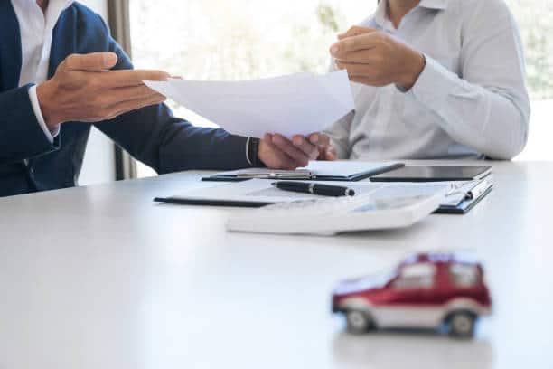 Assureur et jeune conducteur en train de signer les papiers d'assurance voiture